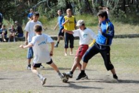 Мальчишки гоняют мяч с футболистами